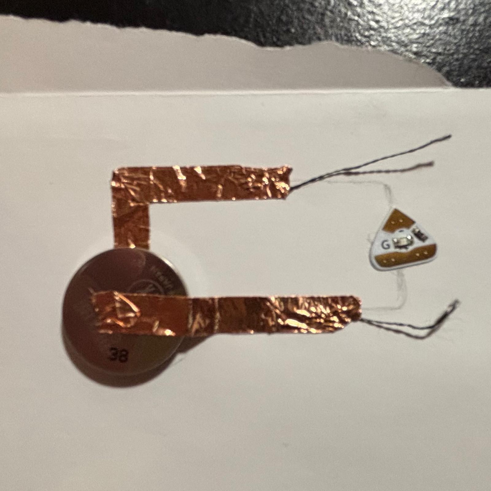 Attached both strings to each end of the copper tape and connect them to the LED according to the '+' and '-' symbols